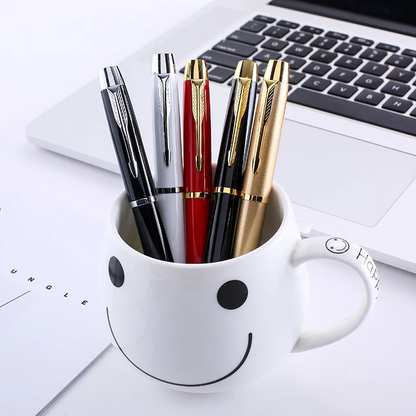 5 pens in a mug with a laptop behind